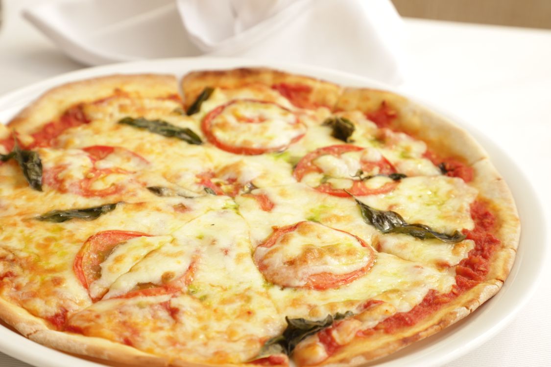 Świeża pizza z mozzarellą, pomidorami i bazylią